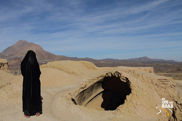 Tourist in Abaya enjoying the caving in of houses at Kharanaq, Iran