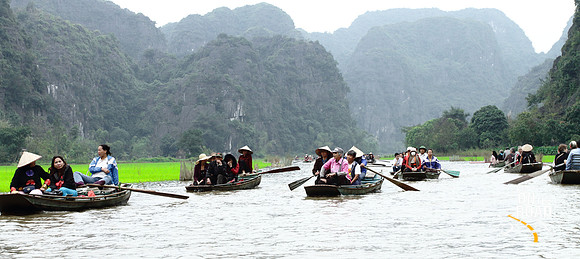 Tourists from all over the world enjoy the beauty of Tam Coc river, Vietnam