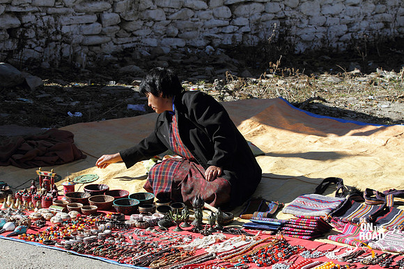 Street hawker selling her wares in front of Jampey Lakhang, Bumthang