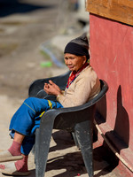 An elderly Arunachal Pradesh tribal women bathes in the morning sun outside of a restaurant