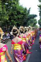 Line of colorfully dressed Balinese women walk on the streets as part of a temple procession