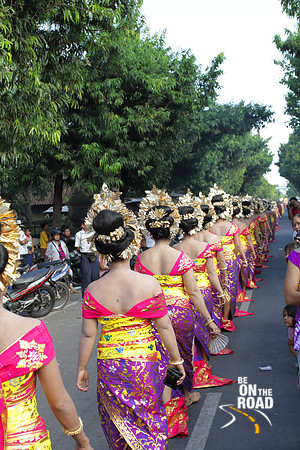 Line of colorfully dressed Balinese women walk on the streets as part of a temple procession